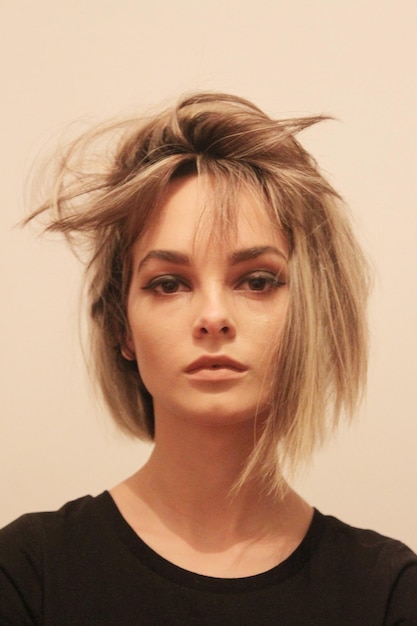 Retrato de una mujer con el cabello desordenado contra un fondo beige
