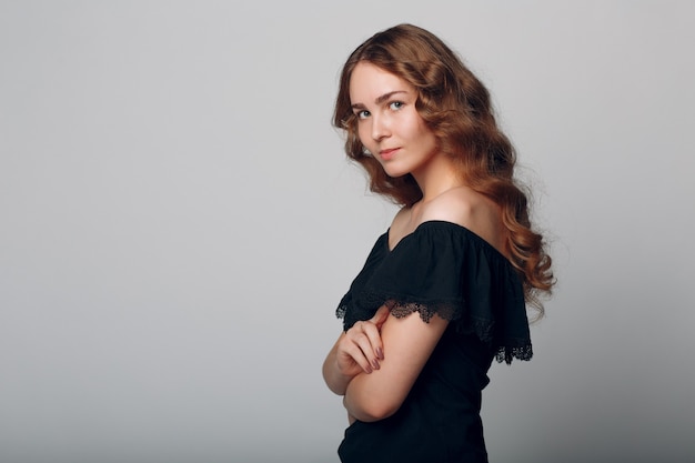 Retrato de mujer con cabello ondulado sobre fondo gris.