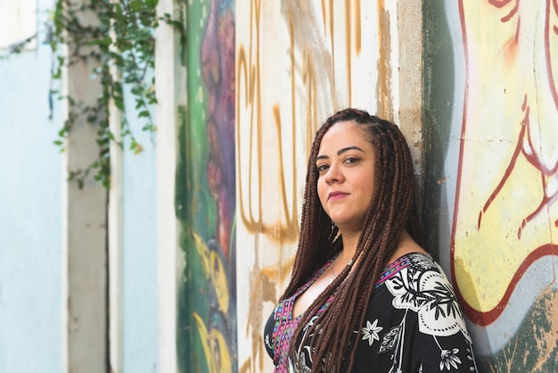 Retrato de una mujer con el cabello trenzado apoyado en una pared de color Turista en viaje Pelourinho Brasil