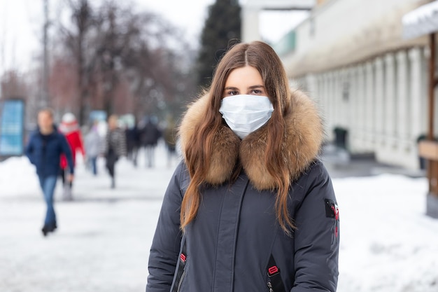 Retrato de mujer caminando por la calle en invierno con una máscara protectora para protegerse contra enfermedades infecciosas Protección contra resfriados gripe contaminación del aire Concepto de salud