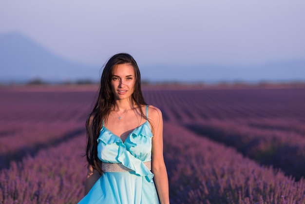 retrato de mujer de campo de flores de lavanda en vestido cyand divirtiéndose y relájese en el viento en el campo de flores púrpura