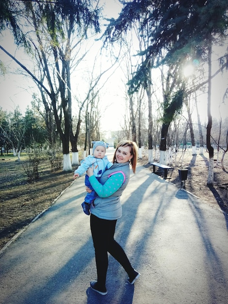 Foto retrato de una mujer cargando a un bebé en un sendero en un parque