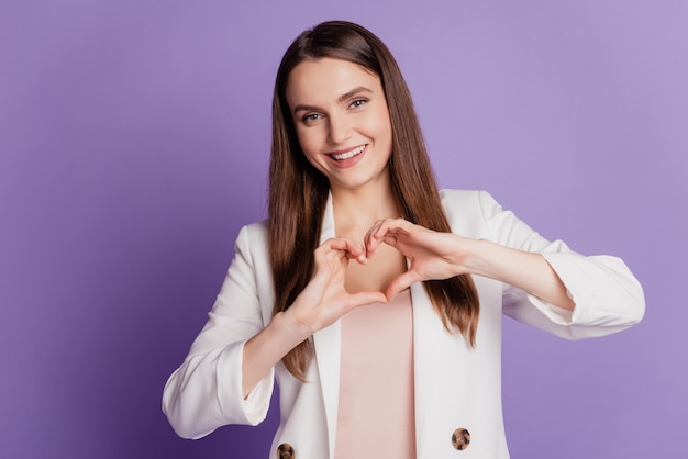 Retrato de mujer cariñosa con traje formal posando en la pared violeta de cerca