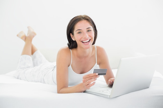 Retrato de una mujer casual haciendo compras en línea en la cama