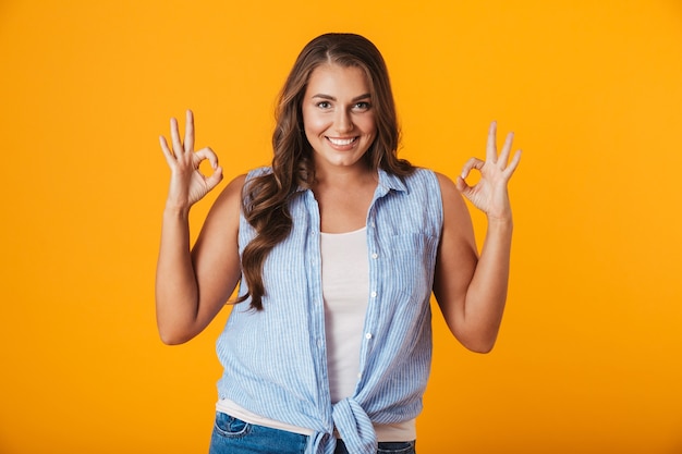 Retrato de una mujer casual joven alegre, mostrando gesto ok