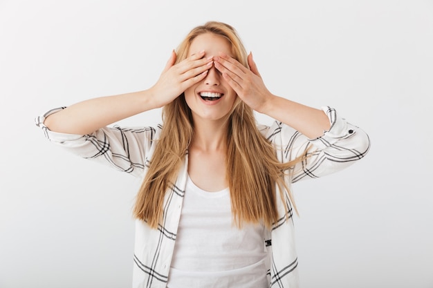 Retrato de una mujer casual joven alegre que cubre los ojos