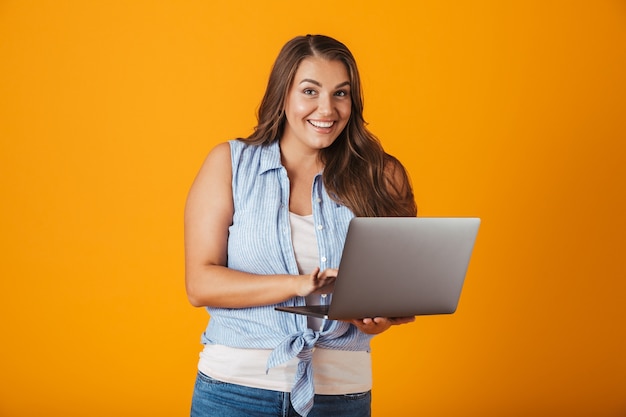 Foto retrato de una mujer casual joven feliz, sosteniendo la computadora portátil