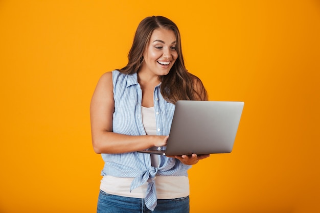 Retrato de una mujer casual joven feliz, sosteniendo la computadora portátil