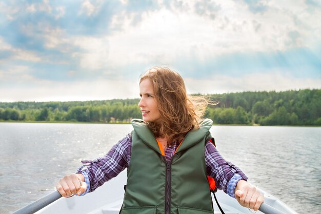 Retrato de una mujer en un chaleco salvavidas navegando en un barco y remos