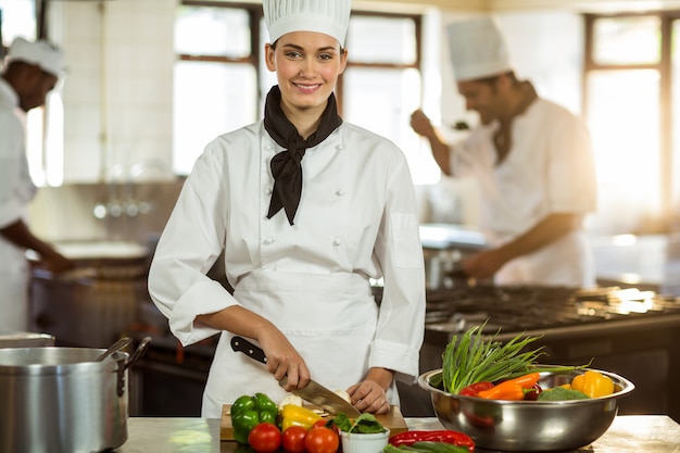 Retrato de mujer chef cortar verduras