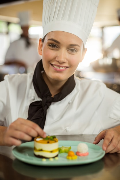 Retrato de mujer chef terminando platos de postre