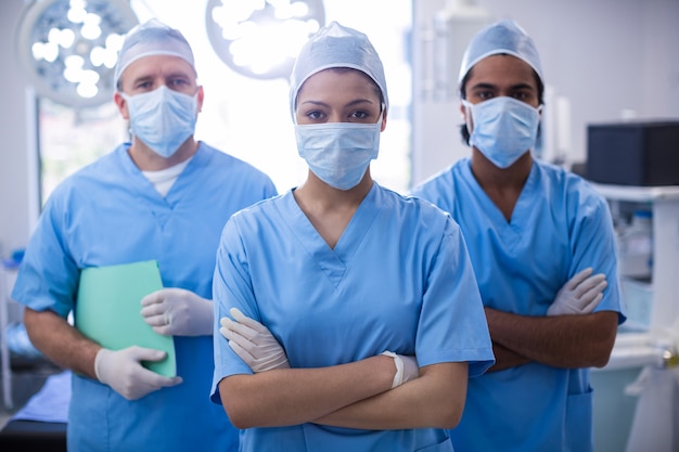 Foto retrato de mujer cirujana de pie con los brazos cruzados en la sala de operaciones