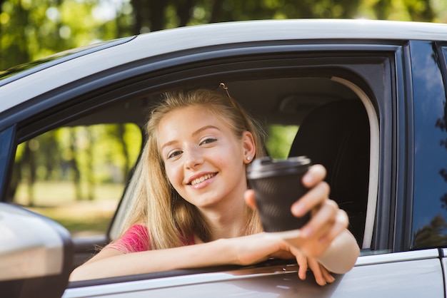 Retrato de mujer en coche con vaso de papel