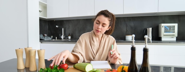 Retrato de una mujer cocinando en la cocina sentada frente a verduras, tomates, calabacines y
