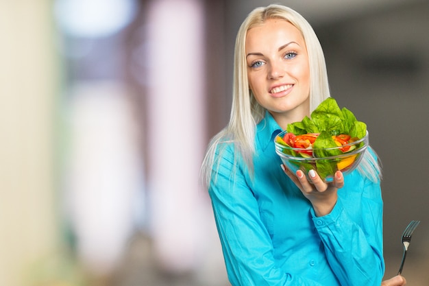 Retrato de mujer comiendo ensalada verde con tomates