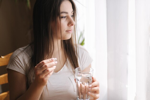 Retrato de mujer comiendo pastillas Mujer en casa en cuarentena Autoaislamiento Mujer Helthy tomar vitamina