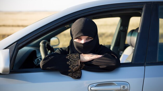 Retrato de una mujer conduciendo un coche. Mujer musulmana en traje nacional