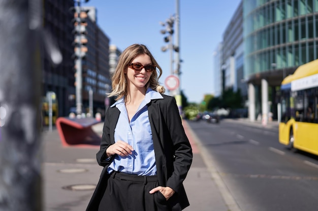 Retrato de una mujer corporativa confiada en una joven vendedora con traje y gafas de sol que parece segura de sí misma