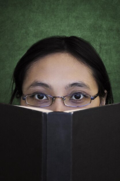 Foto retrato de una mujer cubriendo la cara con un libro abierto