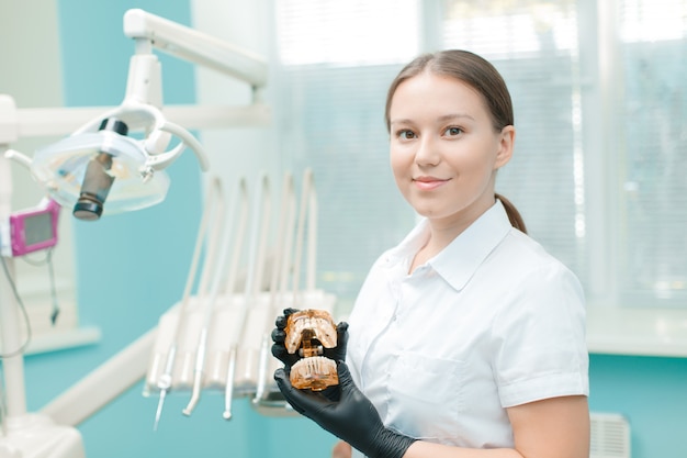 Retrato de mujer dentista en clínica. Médico joven de pie en su oficina.