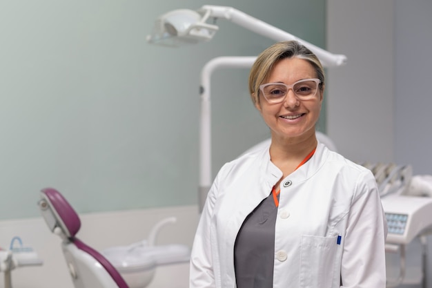 Retrato de mujer dentista mirando a la cámara dentro de la clínica dental