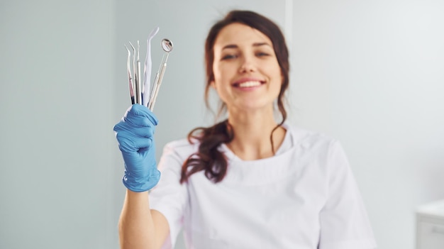 Retrato de mujer dentista profesional con equipo que está parado en el interior