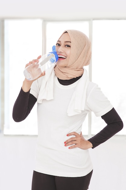 Retrato de mujer deportiva asiática bebiendo agua mineral después del entrenamiento