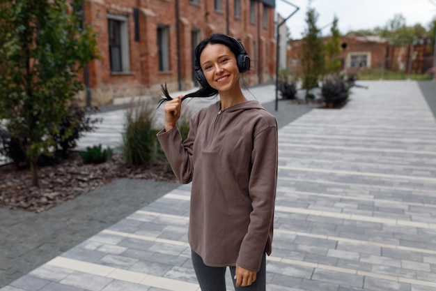 Retrato de una mujer deportiva feliz en auriculares al aire libre