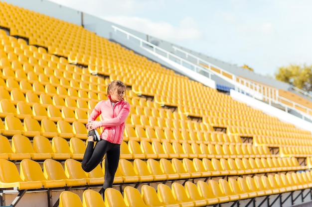 Retrato de una mujer deportiva haciendo ejercicios de calentamiento en el estadio