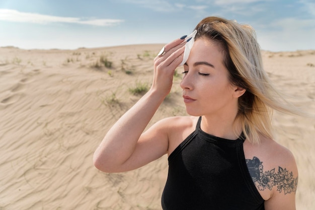 Retrato de una mujer en un día soleado en el desierto, limpiándose el sudor de la frente con un pañuelo