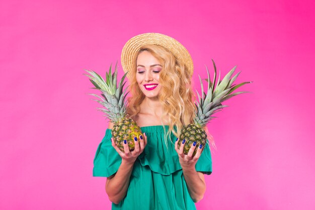 Retrato de mujer divertida y piña sobre pared rosa. Verano, dieta y concepto de estilo de vida saludable.