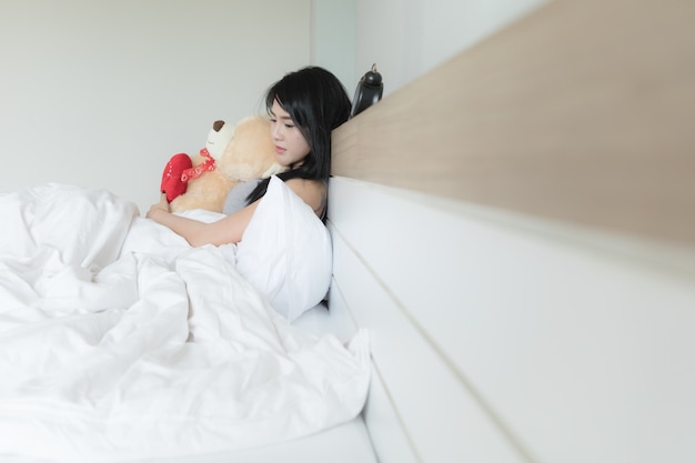 Retrato de una mujer durmiendo abrazando un oso de peluche