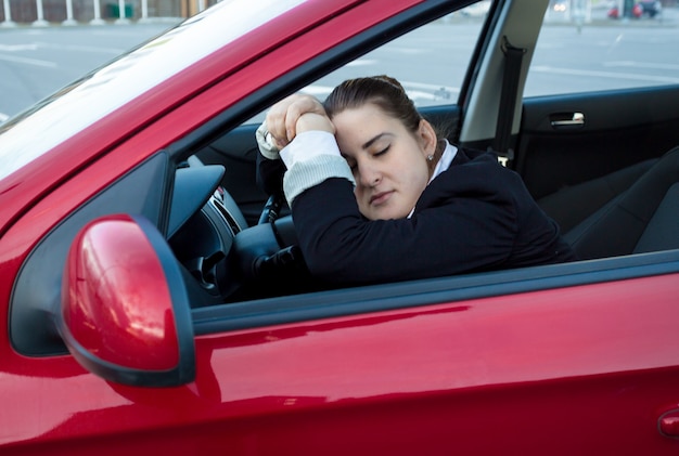 Retrato de mujer durmiendo en el coche en el asiento del conductor