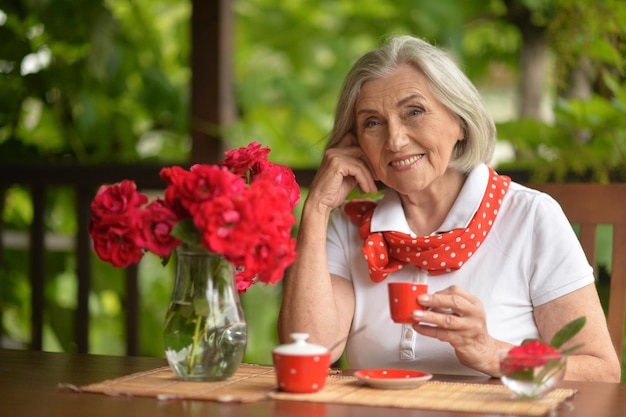 Retrato de una mujer de edad feliz tomando café