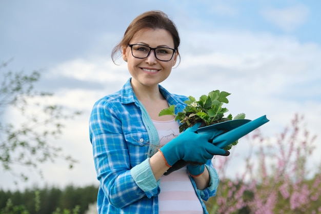 Retrato de mujer de edad media en el jardín con herramientas