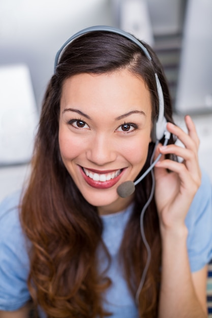 Retrato de mujer ejecutiva de servicio al cliente hablando por auriculares en el escritorio