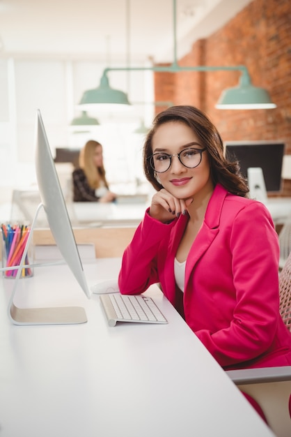 Retrato de mujer ejecutiva sonriente sentados frente al escritorio