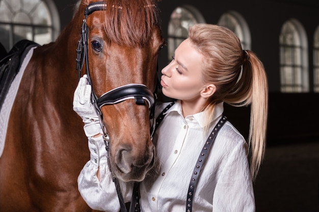 Retrato de una mujer elegante abrazando a un caballo de pura sangre. Concepto de amor y cuidado. Técnica mixta