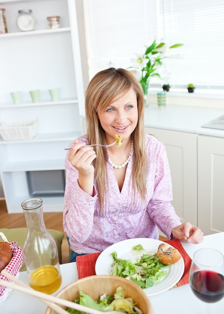 Retrato de una mujer elegante comiendo una ensalada en la cocina