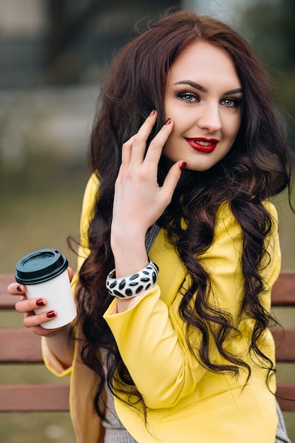 Retrato de mujer elegante en traje de glamour brillante de lujo posando en un banco del parque