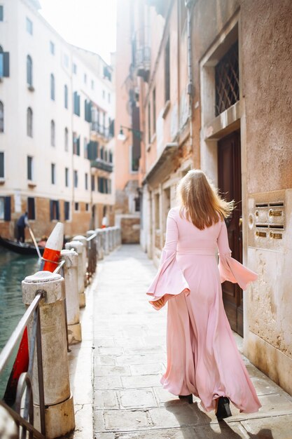 Retrato de una mujer elegante con vestido rosa camina por las soleadas calles de Venecia Concepto de viaje