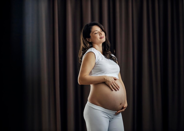 Retrato de una mujer embarazada abrazando su barriga llena de estrías
