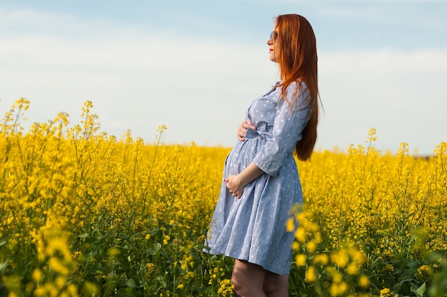 Retrato de mujer embarazada en el campo amarillo