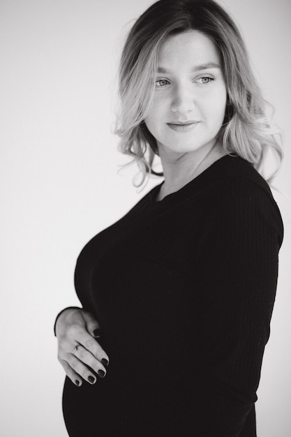 Retrato de mujer embarazada en estudio sobre fondo blanco hermosa futura madre puso sus manos