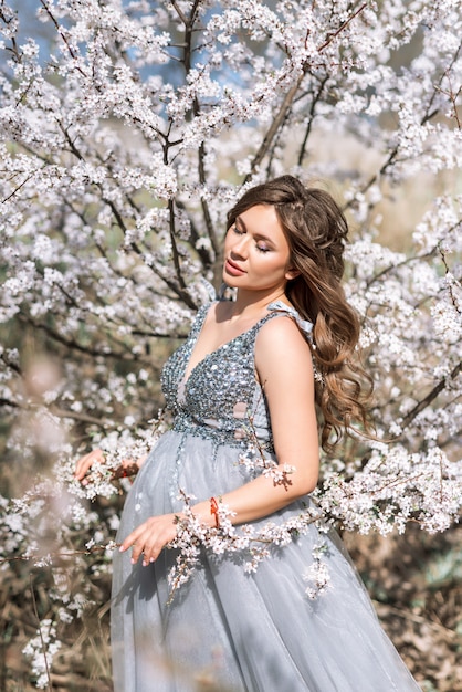 Retrato de una mujer embarazada en un floreciente jardín de primavera