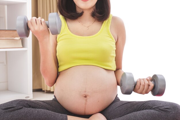 Retrato de mujer embarazada haciendo ejercicio con pesas