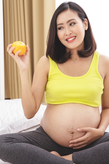 Retrato de mujer embarazada con naranja fresca