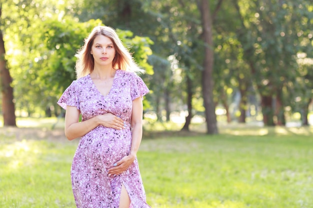 Retrato de una mujer embarazada con un vestido en el parque