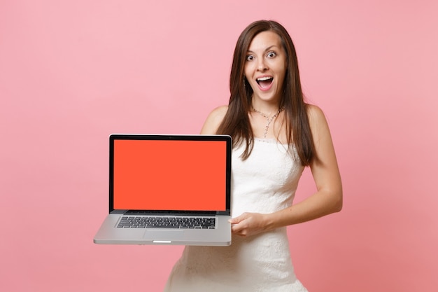 Retrato de mujer emocionada en vestido blanco sostenga la computadora portátil con pantalla vacía negra en blanco