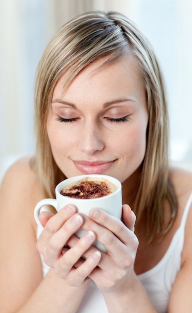 Retrato de una mujer encantada bebiendo un café